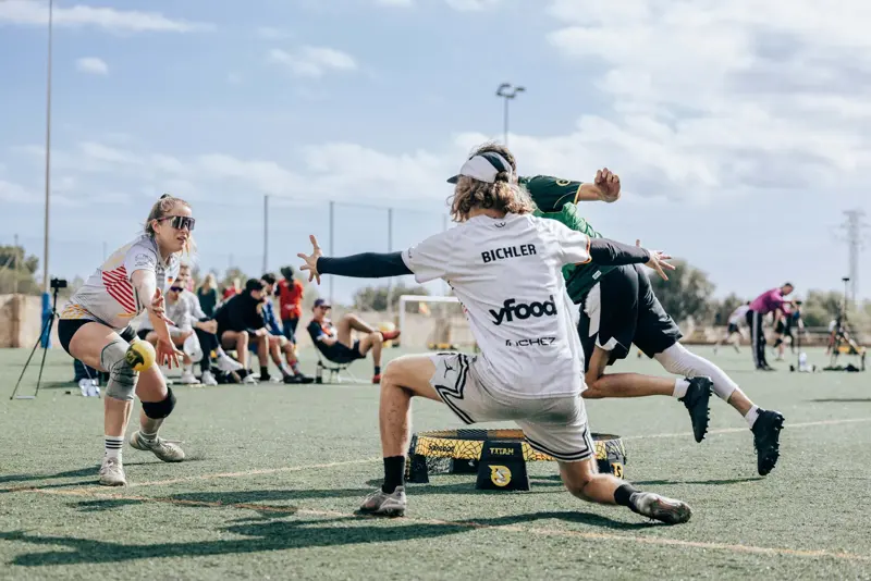 Bichler of Germany in a white yfood shirt, arms spread, defending at the roundnet