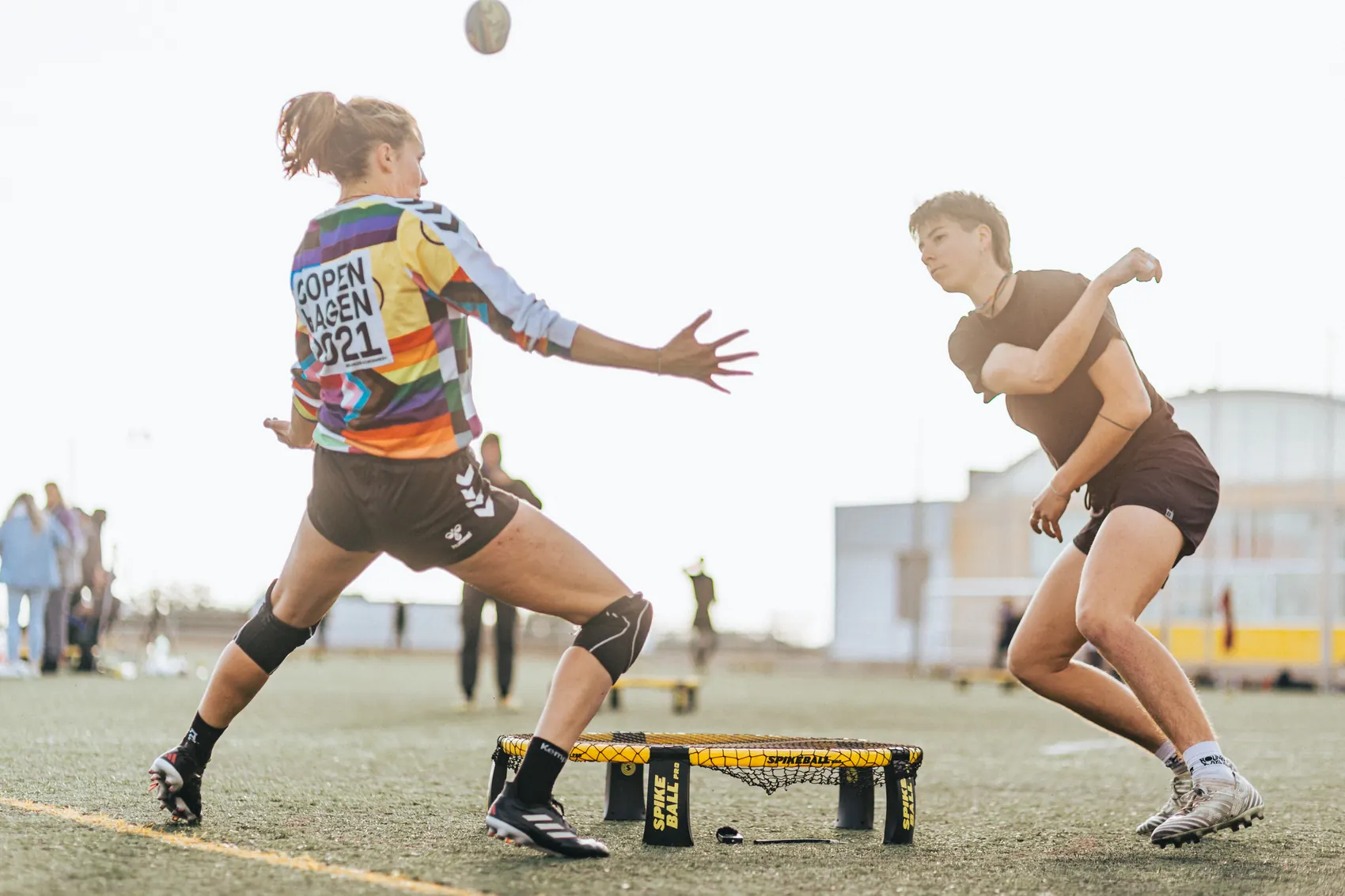 Two roundnet players either side of the net, one reaching out to defend as the other strikes the ball.